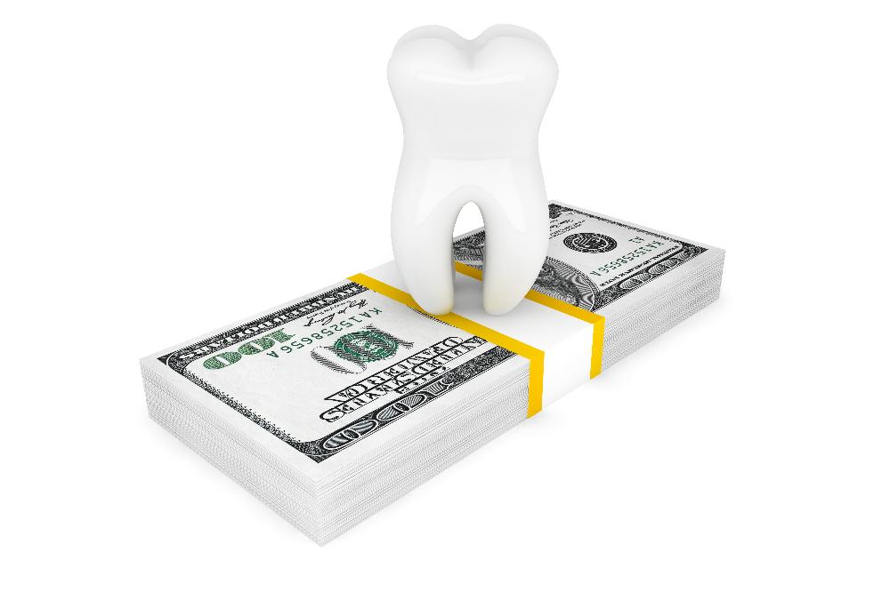 close up of cartoon tooth on stack of dollars | cosmetic dentist high point