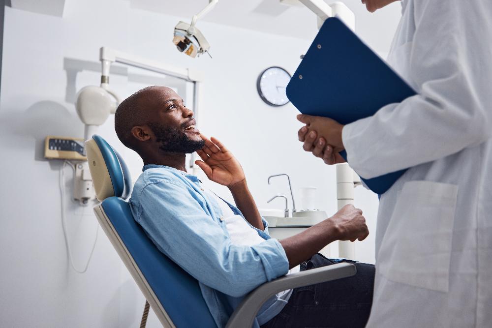 man sitting in exam chair touching his face | high point dentist