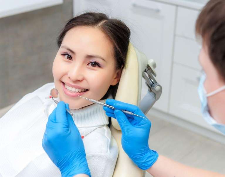 woman sitting in exam chair smiling | dentist in high point